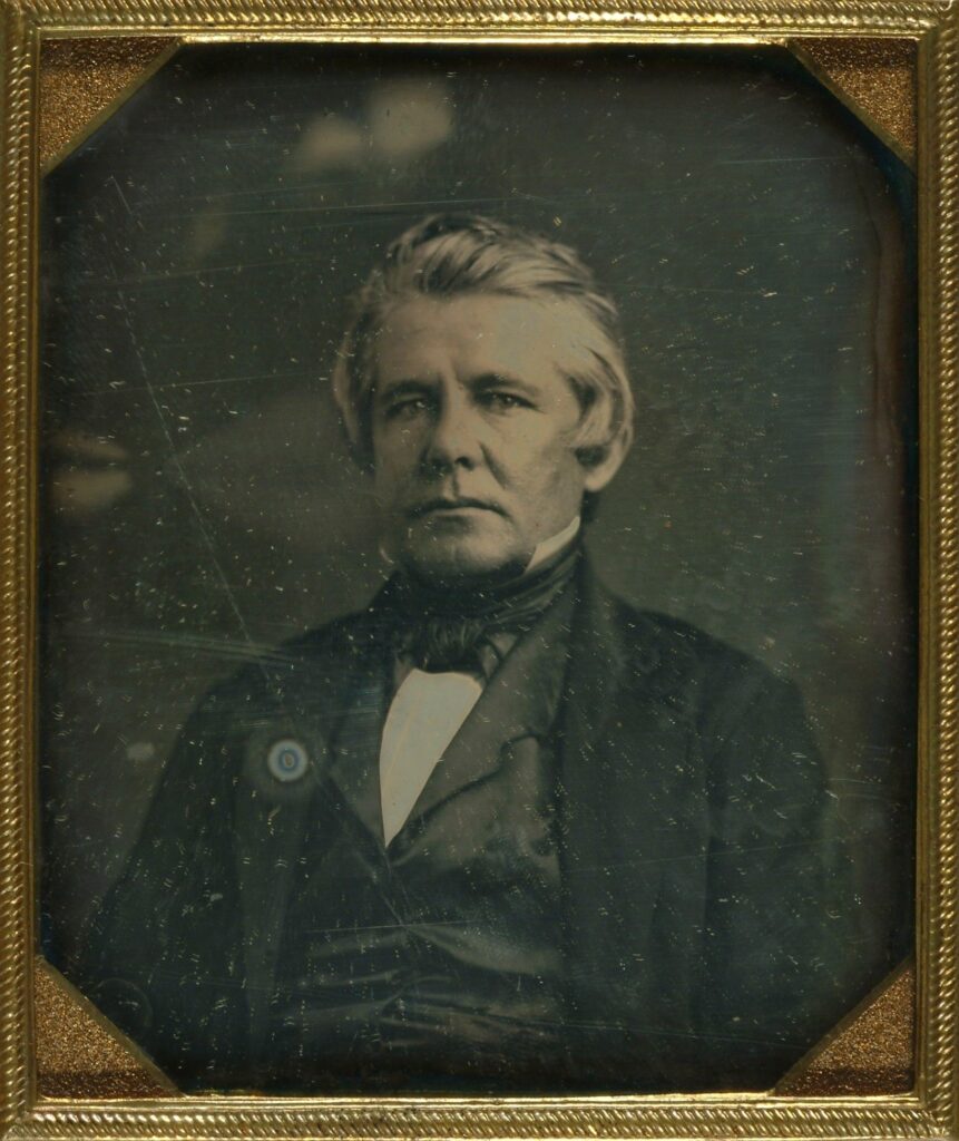 A daguerreotype of William McClure Thomson in a black 19th-century suit, looking stoically into the camera. 